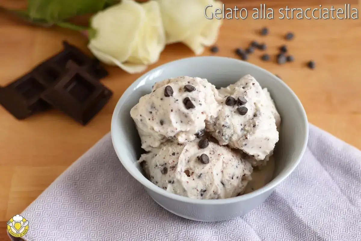 Coppa di gelato alla stracciatella fatta in casa, con gocce di cioccolato fondente e due rose bianche sullo sfondo.