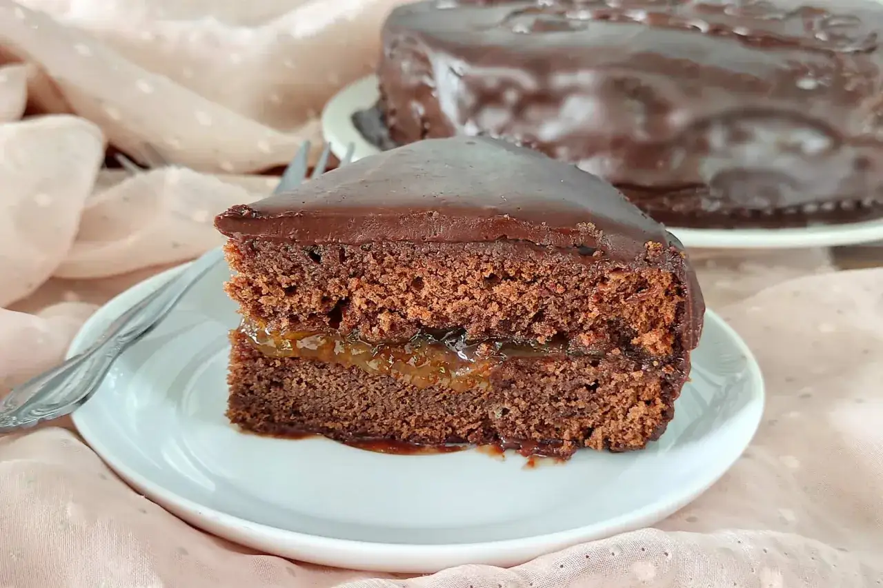 Una fetta di torta Sacher, con la sua glassa al cioccolato lucida e il ripieno di marmellata d'albicocca, pronta per essere gustata.