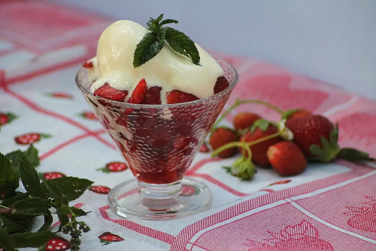 Coppa di fragole fresche e gelato alla vaniglia, guarnita con menta. Un dolce estivo perfetto.