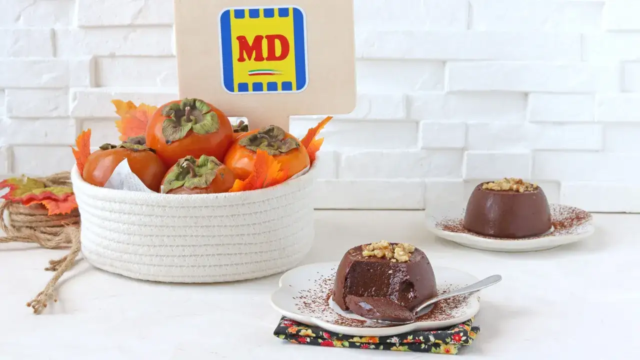 Delizioso budino cachi e cacao, guarnito con noci e cacao in polvere, accanto a cachi freschi in un cesto.