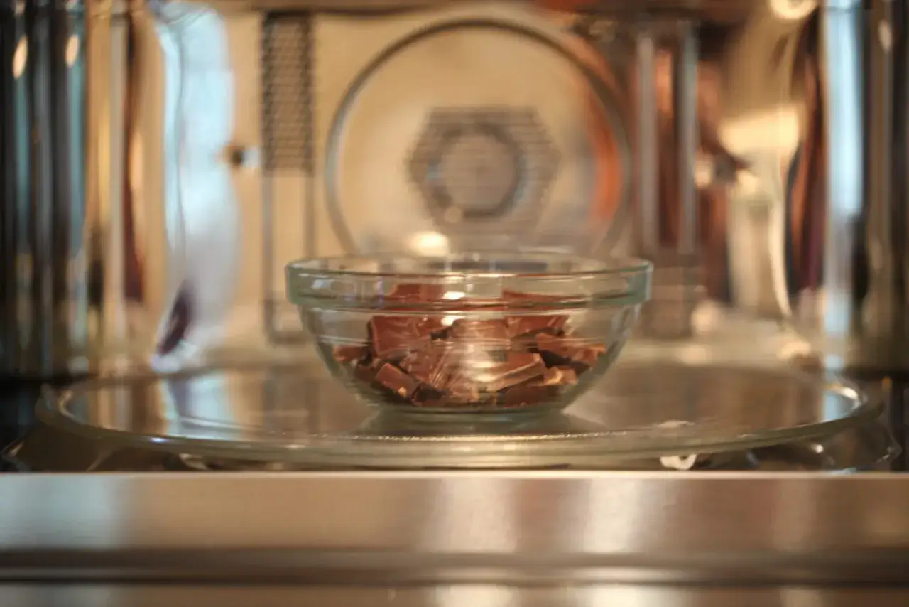 Cioccolato a pezzi in una ciotola di vetro pronta per essere sciolto nel microonde.