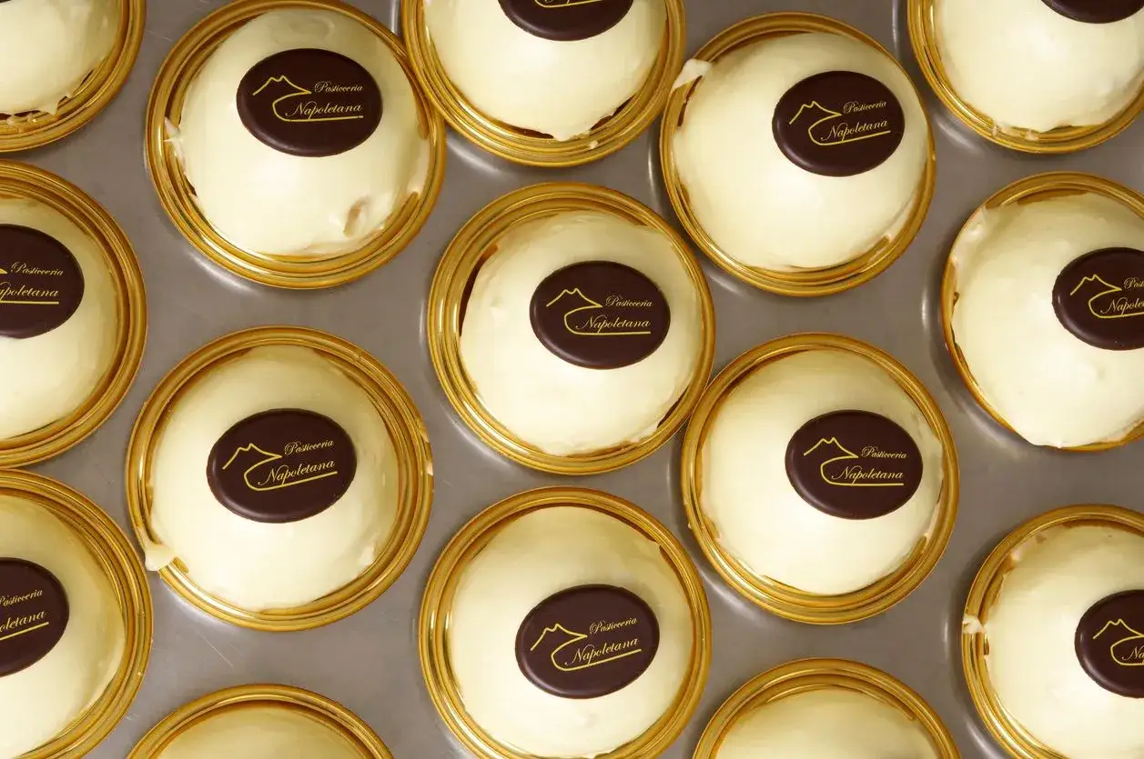 Delizie al limone, dolcetti bianchi e rotondi, guarniti con un ovale di cioccolato con il logo