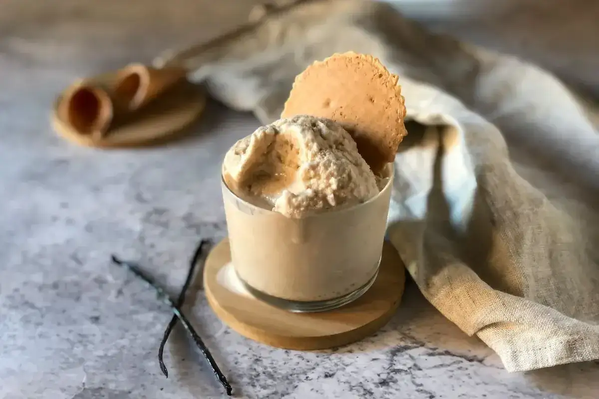 Delizioso gelato con panna vegetale, guarnito con un biscotto croccante e bacche di vaniglia.