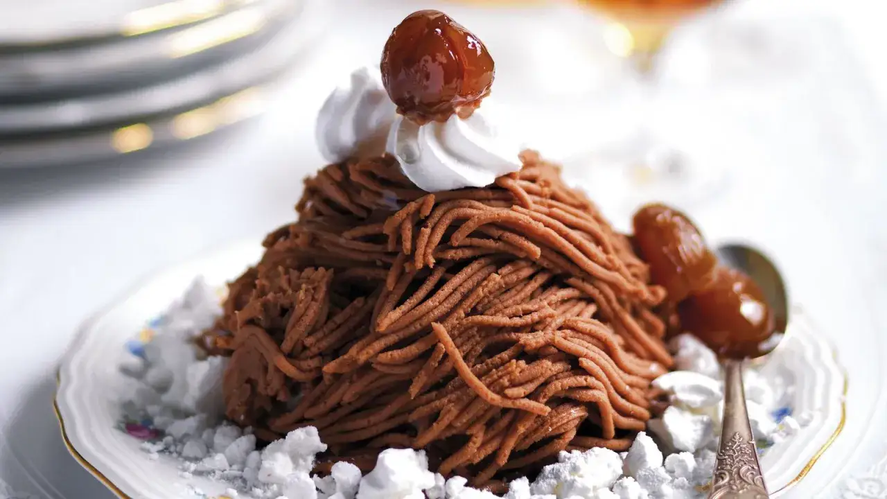 Un delizioso montblanc dolce, una montagna di crema di castagne con panna e canditi, su un piatto elegante.