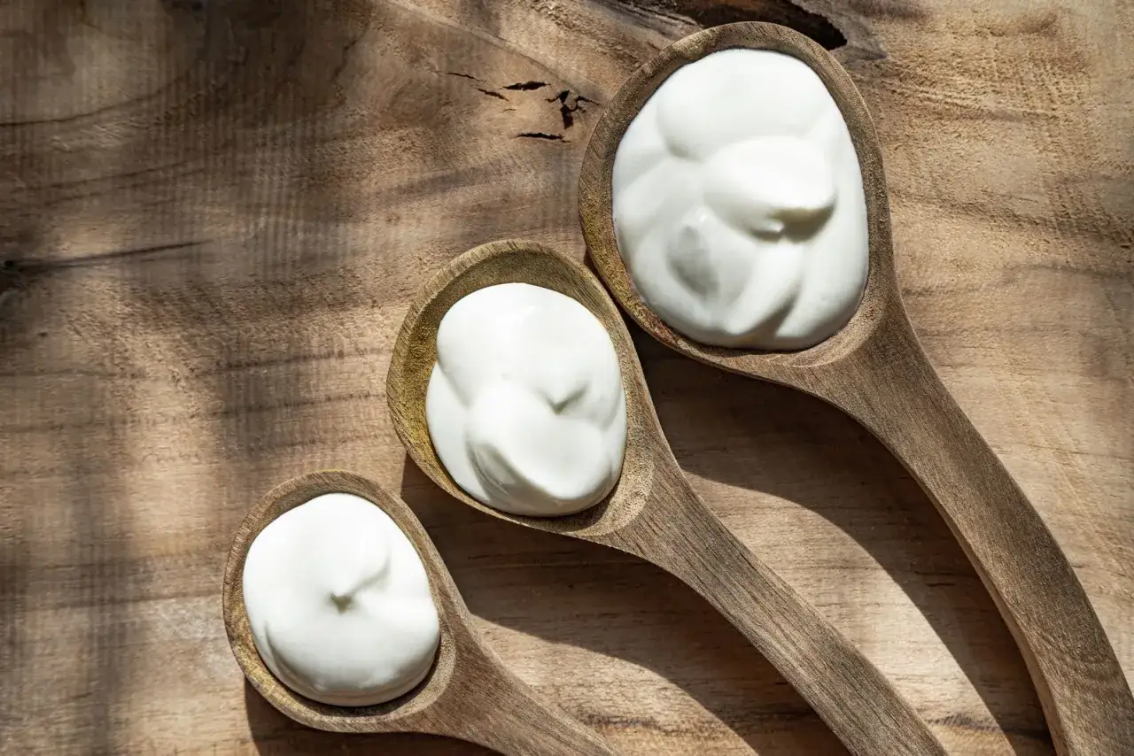 Tre cucchiai di legno con panna, uno più grande dell'altro, illustrano la differenza tra panna fresca e panna da cucina.
