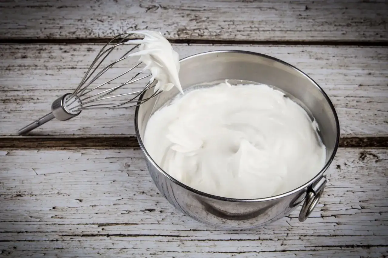 Panna fresca per dolci fatta in casa, montata a neve con frusta, pronta per creare dessert deliziosi.