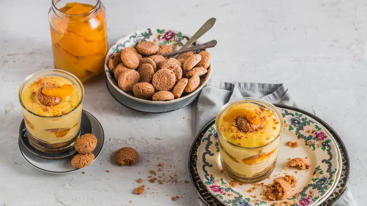 Delizioso tiramis&ugrave; alle pesche in bicchiere, con amaretti e pesche sciroppate.