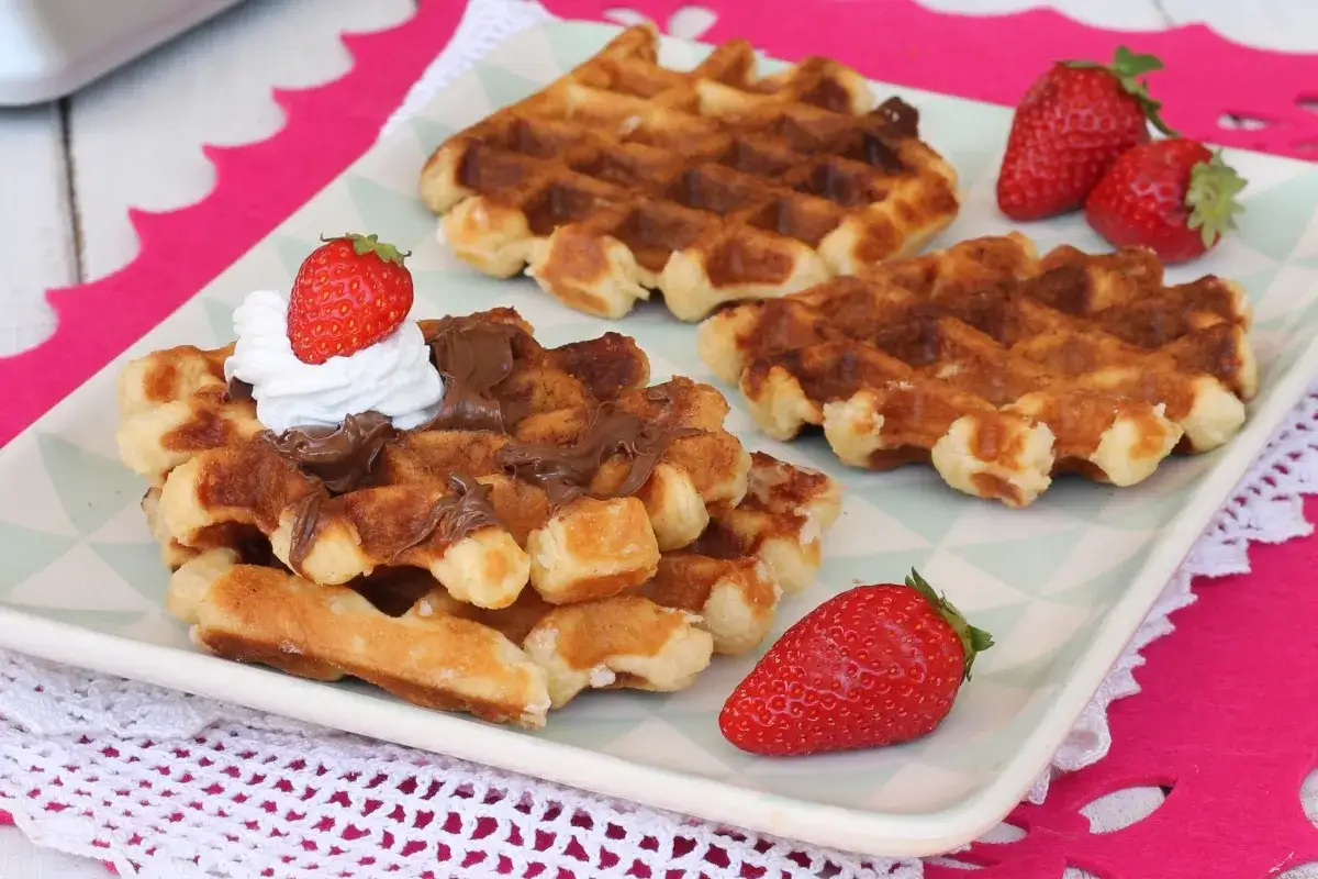 Waffle ricetta originale belga con crema al cioccolato, panna e fragole fresche. Un dolce invitante e goloso.