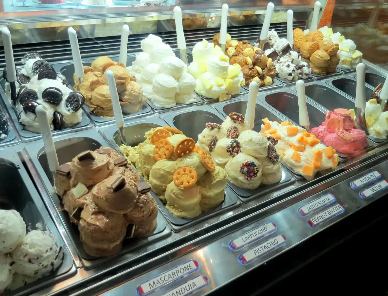 Vetrina di gelati artigianali con gusti vari. In primo piano, un gelato al pistacchio, perfetto abbinamento con altri gusti.