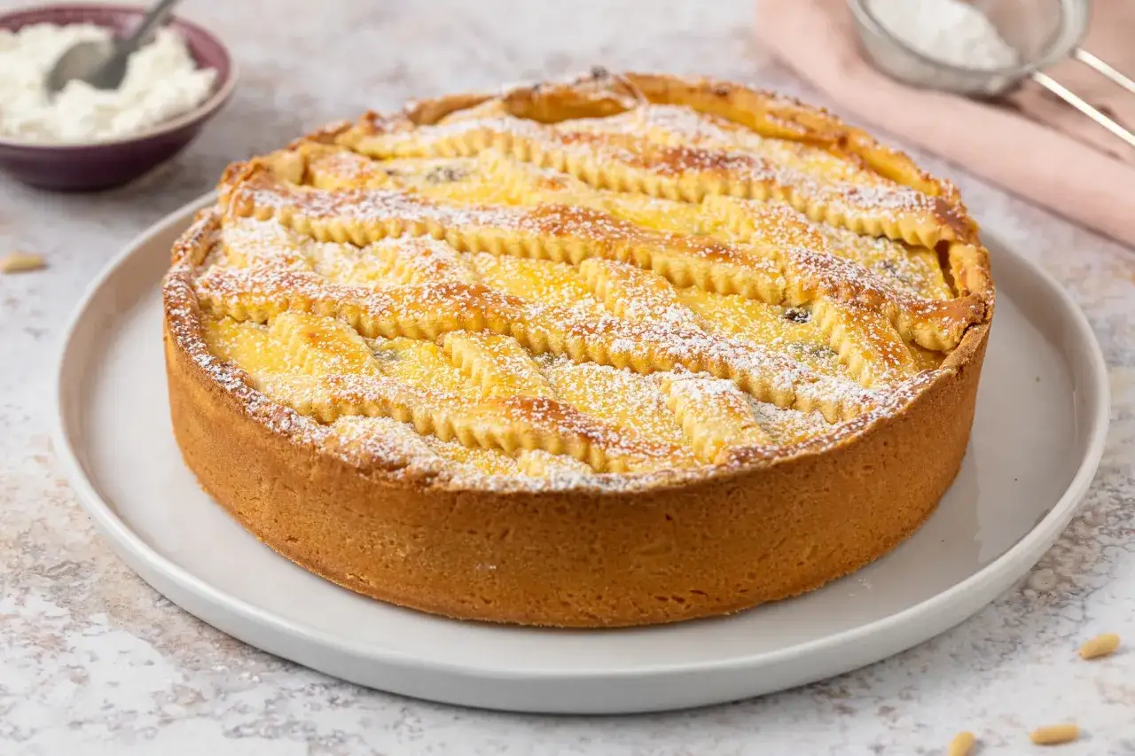 Deliziosa crostata di ricotta, con la sua crosta dorata e il ripieno cremoso, cosparsa di zucchero a velo.