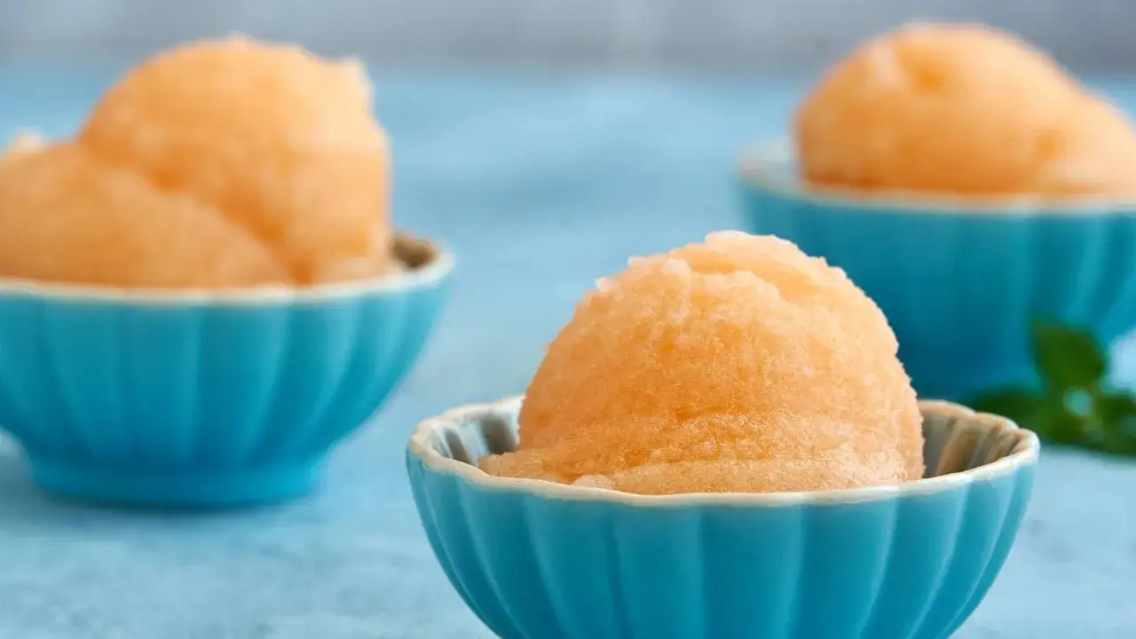 Tre coppette blu con sorbetto melone, un dolce fresco e dissetante per l'estate.