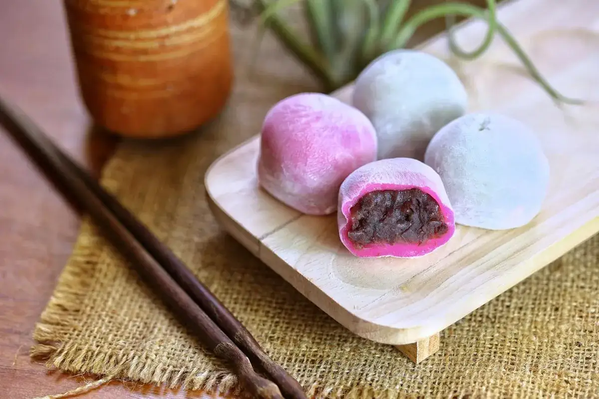 Deliziosi mochi rosa e azzurri, uno aperto rivela il ripieno di fagioli rossi. Una ricetta da provare!